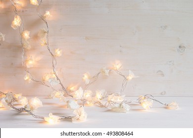 Christmas Lights Burning  On A White Wooden Background. Xmas Background.