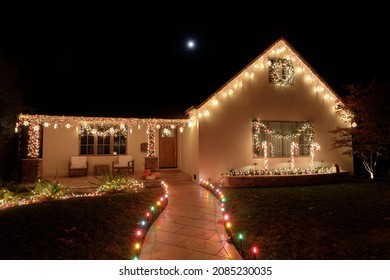 Christmas lights decorating house at night with full moon