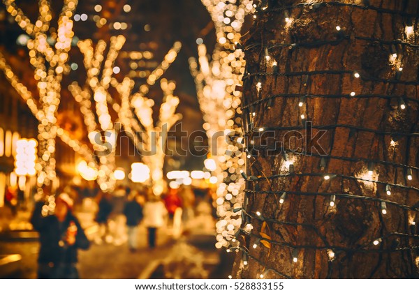 クリスマスの光が木に当たる クリスマスは木の幹の接写 ぼかした背景に街の通りとクリスマスのイルミネーション の写真素材 今すぐ編集