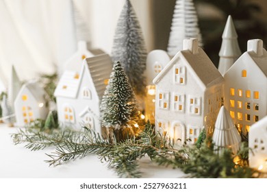 Christmas little ceramic houses, snowy trees and golden lights on dark background in eve. Merry Christmas! Atmospheric Christmas scene, miniature holiday village. Xmas background - Powered by Shutterstock