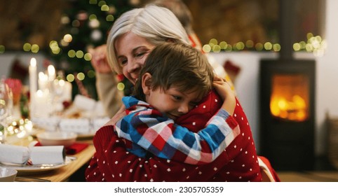 Christmas, love and a grandma hugging her grandchild in the home during the festive season together. Family, children or holiday with a young boy and senior woman in a house to hug while bonding - Powered by Shutterstock