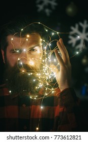 Christmas man with beard on serious face and garland. Party and celebration. New year guy with illuminated wire. Winter holiday and xmas. Garland on santa claus man as decoration. - Shutterstock ID 773612821