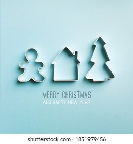 Christmas Minimal Blue Background. Cookie Cutters Tree, House, Gingerbread Man. Text Merry Christmas And Happy New Year.