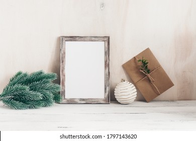 Christmas Minimalistic Home Decor. Retro Styled. Blank Portrait Frame, Fir Branch, Christmas Balls And Craft Envelope. Old White Wooden Table And Shabby Backdrop. Scandinavian Style