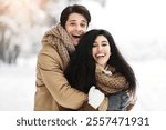 Christmas Mood. Cheerful Couple Of Lovers Embracing Smiling At Camera Standing In Winter Forest.