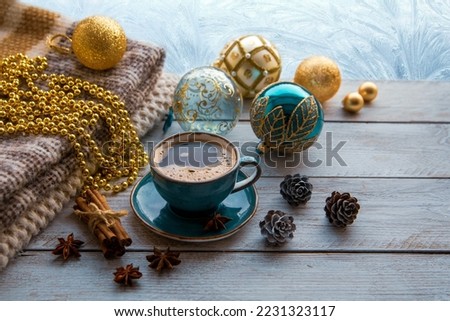 Christmas mood, holiday atmosphere. A cup of coffee, Christmas tree balls, cones, star anise, cinnamon on a wooden windowsill against the background of a window covered with hoarfrost