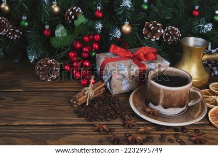 Christmas mood, holiday atmosphere. Red cup of coffee, fir branches with cones, Christmas gifts, star anise on a wooden table background.