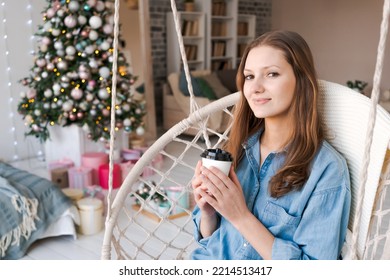 Christmas Morning, Christmas. Girl On Chair Drinks From Disposable Paper Cup. Woman On New Year's Eve In Rustic Retro Living Room. Enjoying Winter Holidays