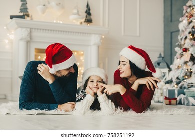 Christmas Morning, Mom And Dad And Their Little Daughter Together On Home , Enjoing Holidays Family People