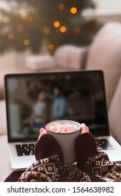 Christmas movie time. Female with cup of hot chocolate watching on laptop screen, vertical panorama, blurred background, copy space