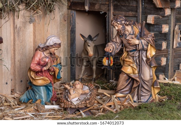 Christmas nativity scene - Jesus Christ, Mary and Joseph. Wooden figurines, donkey in the background.