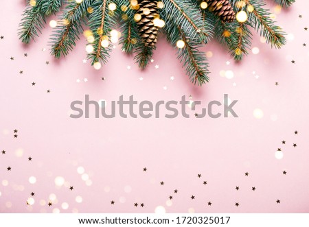 Christmas natural coniferous border with cones and confetti. Festive pink background with sparkles and bokeh lights.