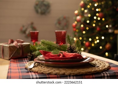 Christmas and New Year 2023, a beautiful setting of the New Year's table in red, against the background of a decorated Christmas tree and a window with a winter landscape