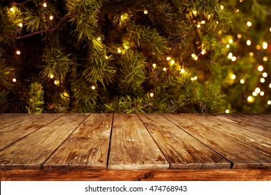 Christmas and New year background with empty dark wooden deck table over christmas tree and blurred light bokeh. Empty display for product montage. Rustic vintage Xmas background. - Powered by Shutterstock