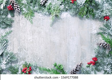 Christmas and New Year background with fir branches, holly and snowfall on wooden white board - Powered by Shutterstock