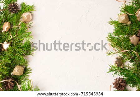 Christmas or New Year background: fir tree branches, gold glass balls, decoration and cones on a white plaster background
