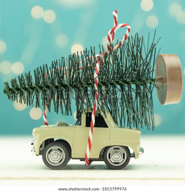 Christmas or New\
year card with toy car and christmas tree miniature and Christmas\
bokeh lights on\
background