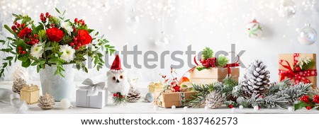Christmas or New Year concept with flower arrangement, gift boxes and Christmas decorations on table. Festive still life.