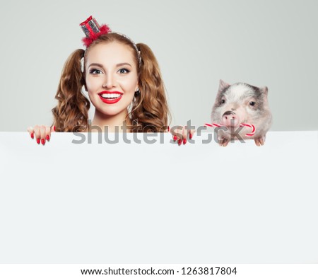 Christmas and New Year concept. Happy woman and pig holding white empty paper boar background. 