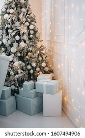 Christmas And New Year Concept - Heap Of Blue Gift Boxes Near Decorated Christmas Tree With Lights. Luxury Living Room Interior With Sofa Decorated Chic Christmas Tree, Gifts. Christmas At Home