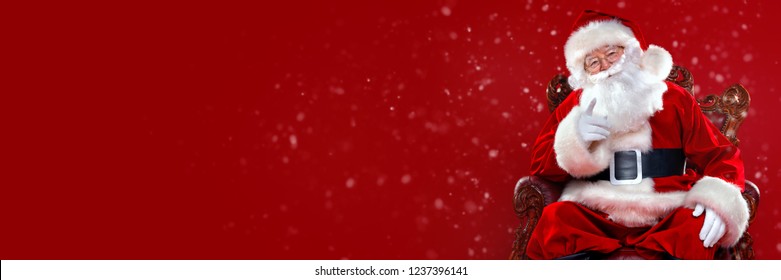 Christmas and New Year concept. Portrait of good old Santa Claus sitting in his armchair. Red background.