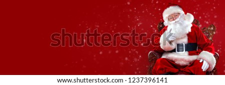 Christmas and New Year concept. Portrait of good old Santa Claus sitting in his armchair. Red background.