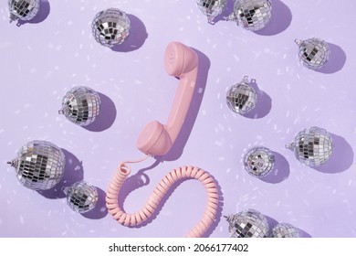 Christmas And New Year Creative Layout With Disco Ball Decoration And Pink Retro Phone Handset On Pastel Purple Background. 80s Or 90s Aesthetic Fashion Concept. Minimal Communication Idea.