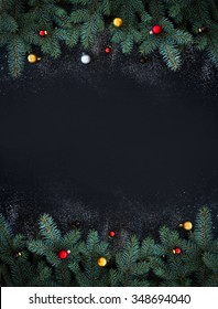 Christmas or New Year decoration background: fur-tree branches, colorful glass balls on black grunge background with copy space
