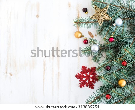 Christmas or New Year decoration background: fur-tree branches, colorful glass balls and glittering stars on white wooden background, top view, copy space