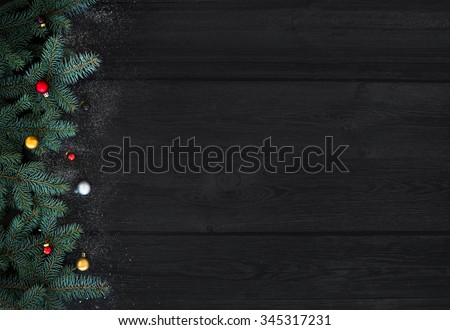 Christmas or New Year decoration background: fur-tree branches, colorful glass balls on black wood background with copy space