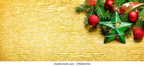 Christmas and new year decoration on golden textured background. Golden holiday banner layout with xmas ornamet and fir tree border. Top view.