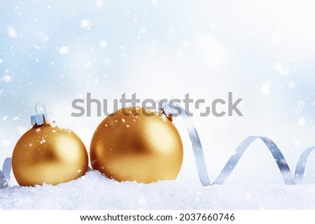 Christmas and New Year greeting card. Holiday ornament, winter decoration. Gold christmas balls with ribbon over snow background, with copy space.
