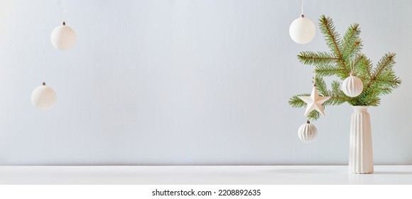 Christmas, New Year home decor. Empty white wall mock up with green fir branches in a vase on a white table. Mock up for displaying works - Powered by Shutterstock