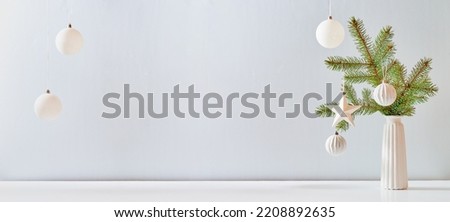 Christmas, New Year home decor. Empty white wall mock up with green fir branches in a vase on a white table. Mock up for displaying works