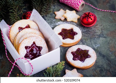 Christmas or New Year homemade sweet present in white box. Traditional Austrian christmas cookies - Linzer biscuits filled with red raspberry jam. Festive decoration. Copy space