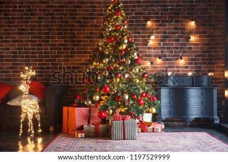Christmas, New Year interior with red brick wall background, decorated fir tree with garlands and balls, dark drawer and deer figure