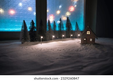 Christmas and New Year miniature house in the snow at night with fir tree. Little toy house on snow with tree and bokeh city lights on background. Christmas decorations. Selective focus - Powered by Shutterstock