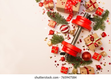 Christmas or New Year on a white background. Composition with dumbbells, gift, red and gold glass  balls, fir tree branches for healthy lifestyle and sport