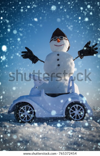 christmas new year snow concept Christmas and\
transportation. Happy holiday celebration. Xmas or christmas\
decoration, aviation. Snowman in winter with toy car, travel and\
vaction. New year\
snowman