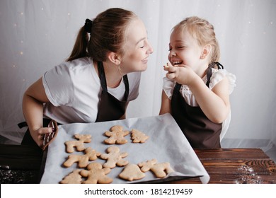 Christmas and New Year traditions concept. Festive food, cooking process, family culinary. Mother and daughter eating fresh gingerbread cookies together