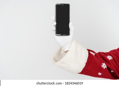 Christmas And New Years Concept. Santa Claus Holds A Mobile Phone In His Hand. No Face Visible. Isolated Background