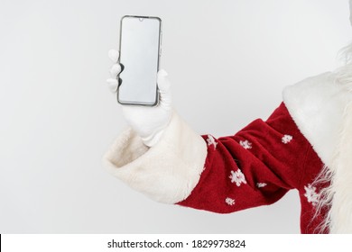 Christmas And New Years Concept. Santa Claus Holds A Mobile Phone In His Hand. No Face Visible. Isolated Background