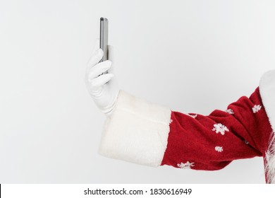 Christmas And New Years Concept. Santa Claus Holds A Mobile Phone In His Hand. No Face Visible. Isolated Background