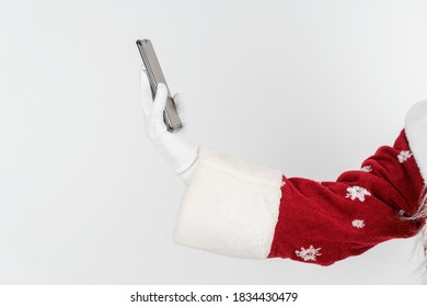 Christmas And New Years Concept. Santa Claus Holds A Mobile Phone In His Hand. No Face Visible. Isolated Background