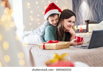 Christmas Online Family Congratulations. Smiling Mother And Son Using Laptop For Video Call Friends And Parents. Christmas Celebration Online.