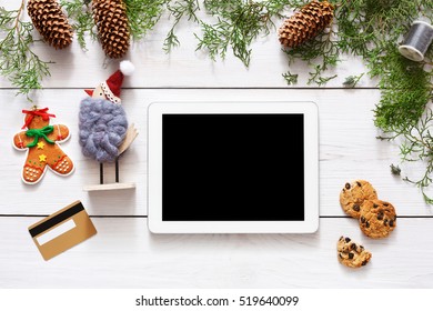 Christmas online shopping background. Tablet screen with copy space top view on white wood, present boxes, gold credit card and cookies. Internet commerce on winter holidays concept - Powered by Shutterstock