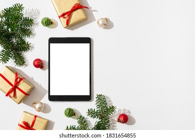 Christmas online shopping concept. Tablet with copy space on white background with Christmas decorations, balls, presents and fir branches. Winter holidays sales background