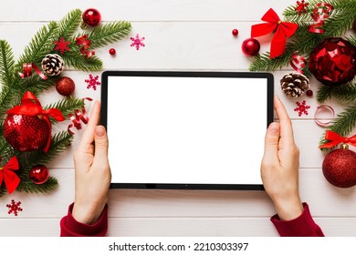 Christmas online shopping from home, female hands holding tablet pc with blank white display top view. woman hand holding tablet with blank screen, Christmas tree and gifts on background. - Powered by Shutterstock