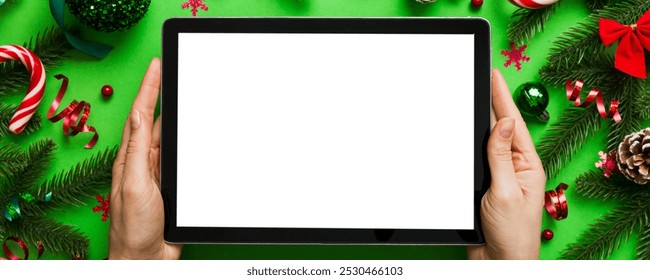 Christmas online shopping from home, female hands holding tablet pc with blank white display top view. woman hand holding tablet with blank screen, Christmas tree and gifts on background. - Powered by Shutterstock