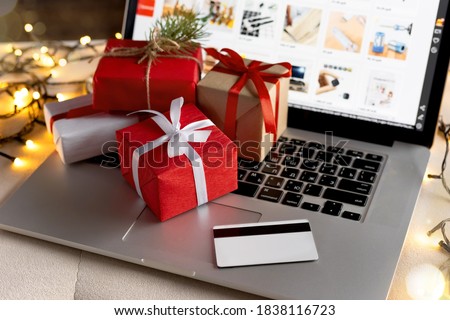 Christmas online shopping, sales and discounts promotions during the Christmas holidays, online shopping at home and lockdown coronavirus. Gifts and credit card on the laptop with blurred bokeh lights